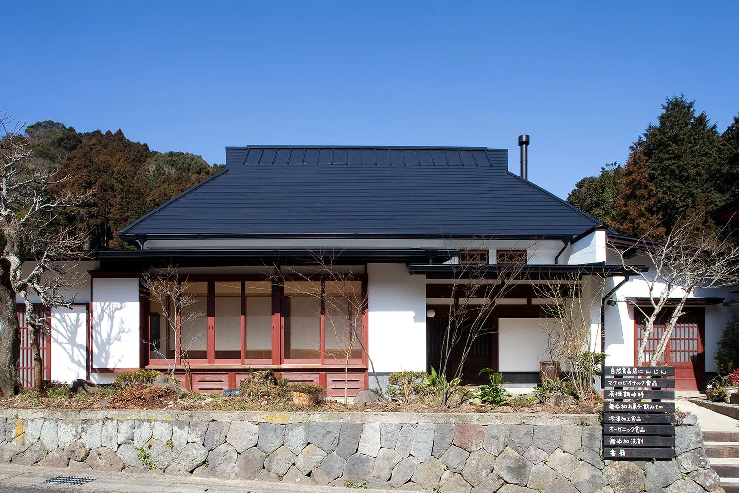 白い漆喰(シックイ)に木製建具が効いています。<br>地元の石で隙間なく積まれた石垣が良い感じです。